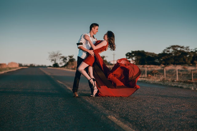 Muž se ženou ve společenských šatech tančící na silnici.jpg