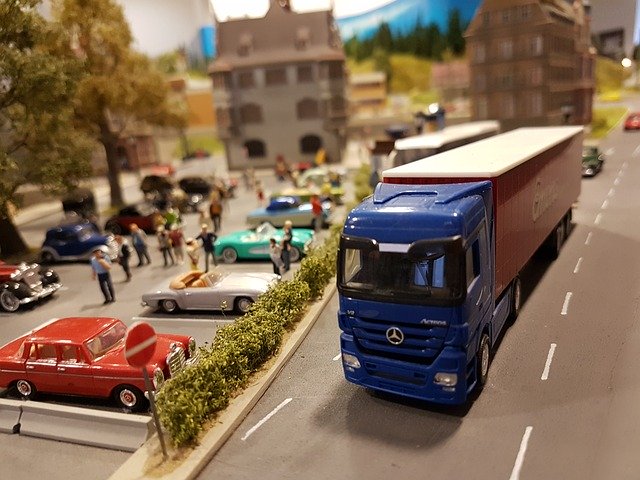 kamion s modrou korbou, maličcí lidi, vyrobeno zřejmě z plastu, městečko